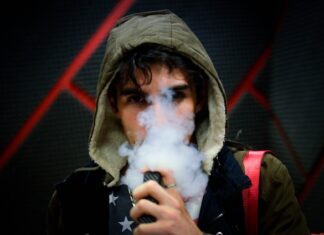 Junger Mann, der eine Vape dampft