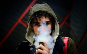 Junger Mann, der eine Vape dampft
