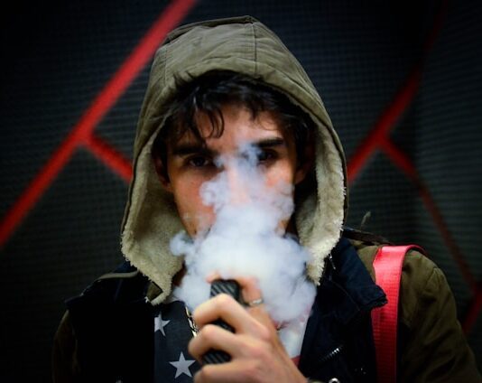 Junger Mann, der eine Vape dampft