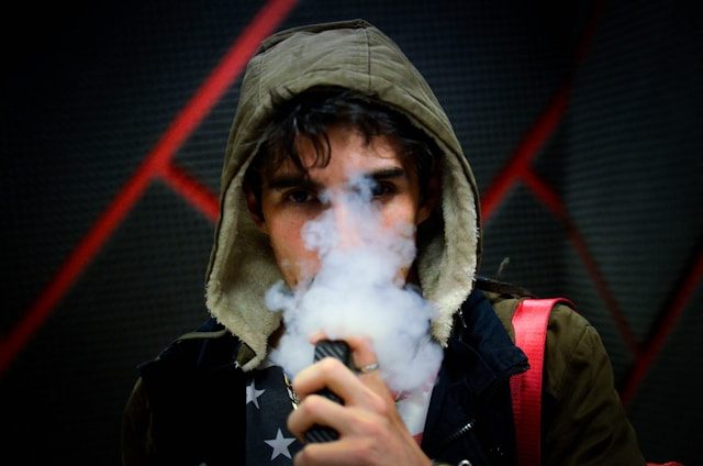 Junger Mann, der eine Vape dampft