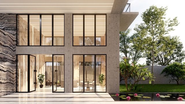 Moderne zweistöckige Villa mit großen bodentiefen Glasfenstern, offenem Wohnbereich und Blick auf einen gepflegten Garten mit Teich und Seerosen.